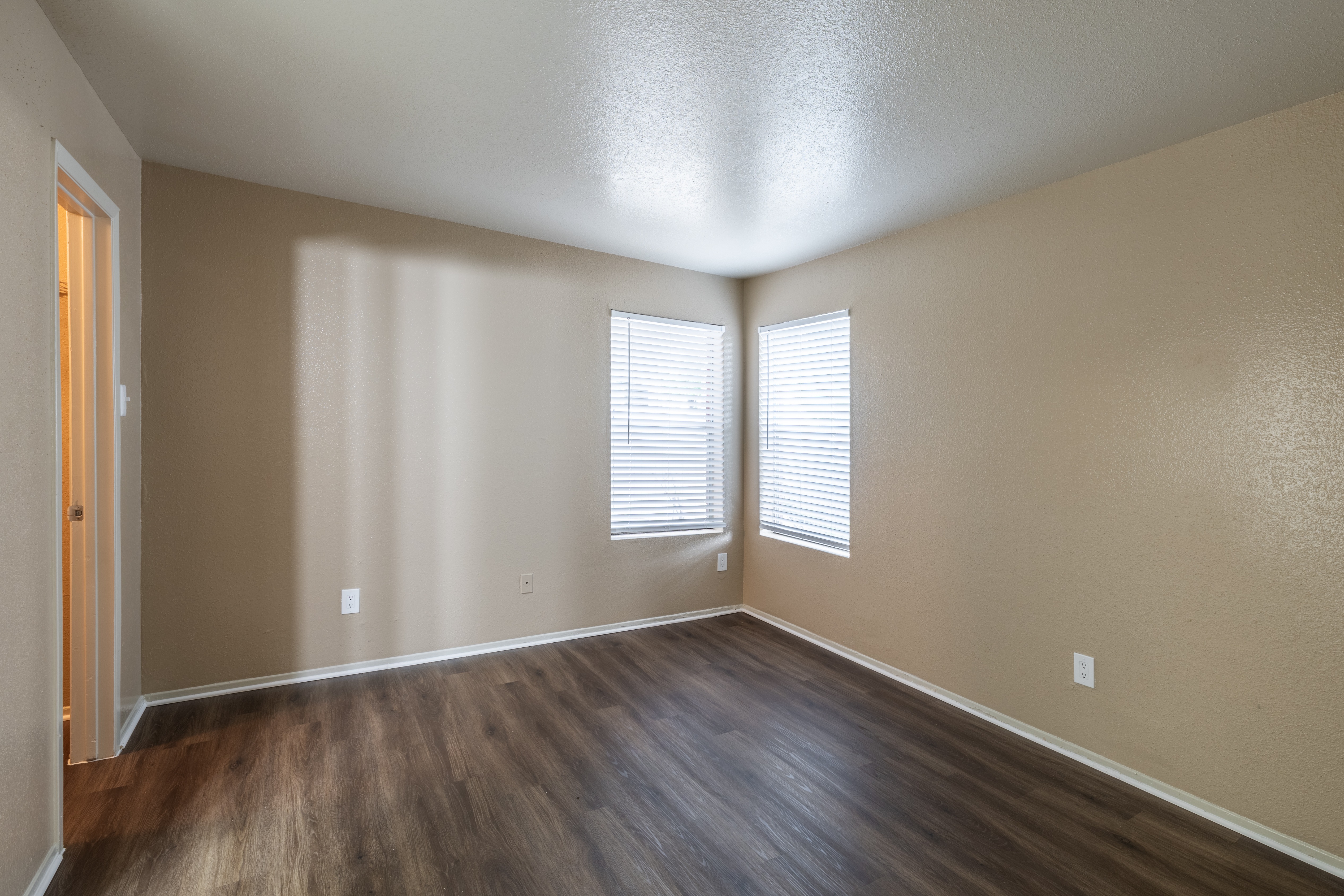 A room with wooden floors and a window with blinds.